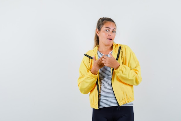 Young female posing while standing in jacket, t-shirt and looking alluring , front view.