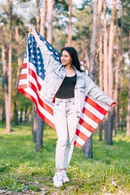 若い女性が公園でアメリカの国旗とポーズ