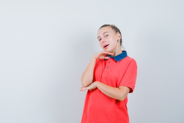 Young female posing with chin propped on hand in t-shirt and looking pretty , front view.