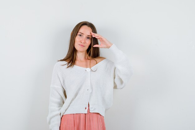 Young female posing with hand over head in cardigan and skirt looking charming isolated