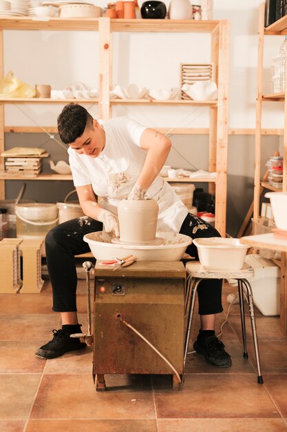 A young female potter sculpting on a potter's wheel in the workshop