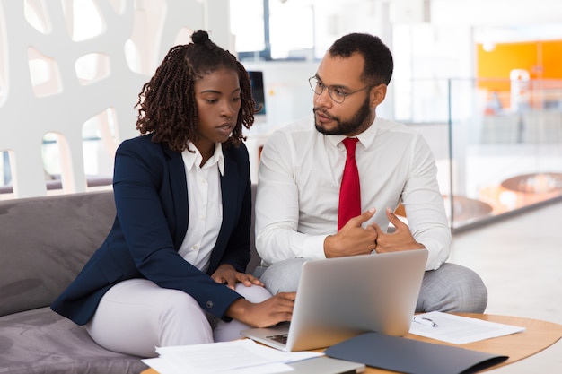 Young female professional consulting male colleague