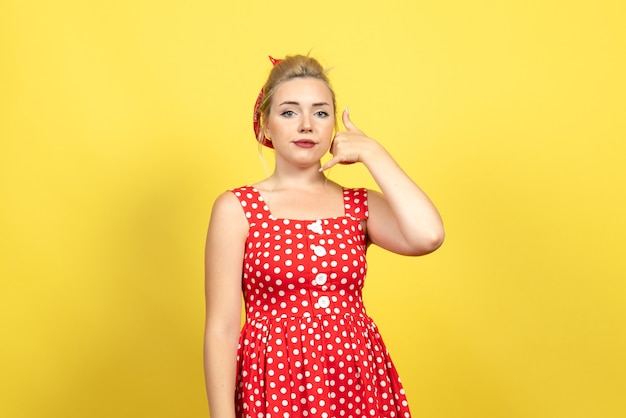 黄色のポーズを呼び出す赤い水玉模様のドレスの若い女性