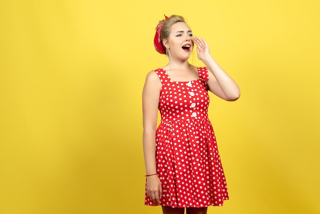 young female in red polka dot dress calling someone on yellow