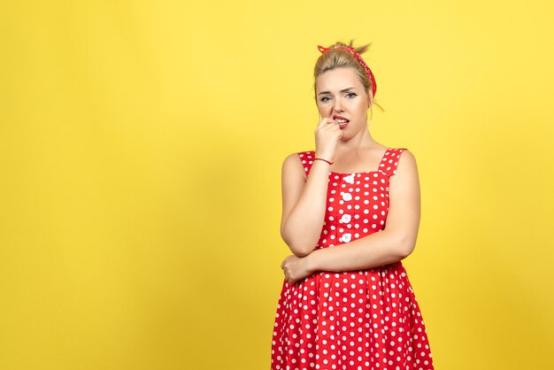 young female in red polka dot dress feeling nervous on yellow