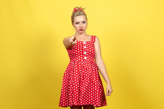 young female in red polka dot dress just standing on yellow