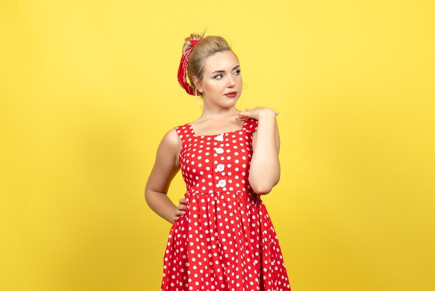 young female in red polka dot dress posing on yellow floor woman emotion color retro fashion cute