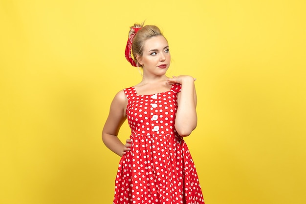молодая женщина в красном платье в горошек позирует на желтом полу женщина эмоция цвет ретро мода мило