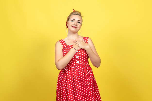 黄色でポーズをとって赤い水玉模様のドレスの若い女性