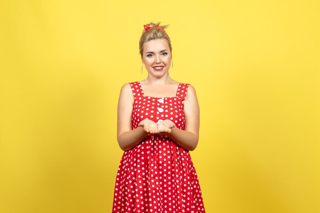 молодая женщина в красном платье в горошек улыбается желтому