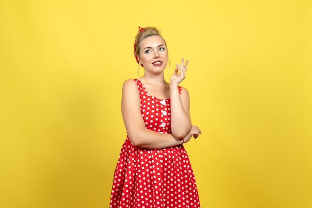 young female in red polka dot dress standing and posing on yellow floor female woman color cute dress fashion