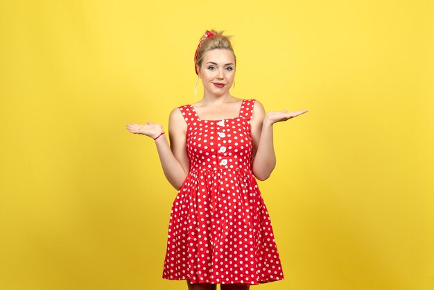 young female in red polka dot dress on yellow