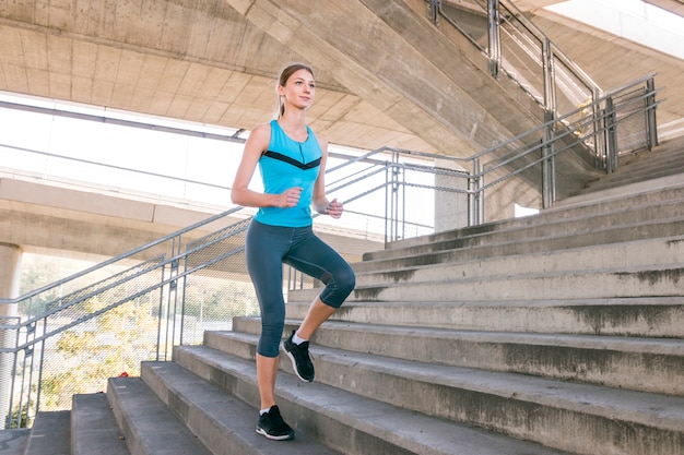 Free photo young female runner jogging on concrete staircase