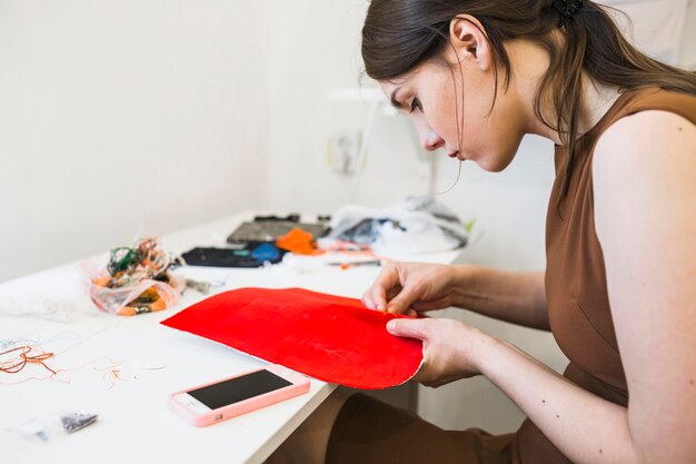 Young female seamstress sewing red cloth