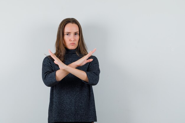 Young female in shirt showing stop gesture and looking serious 