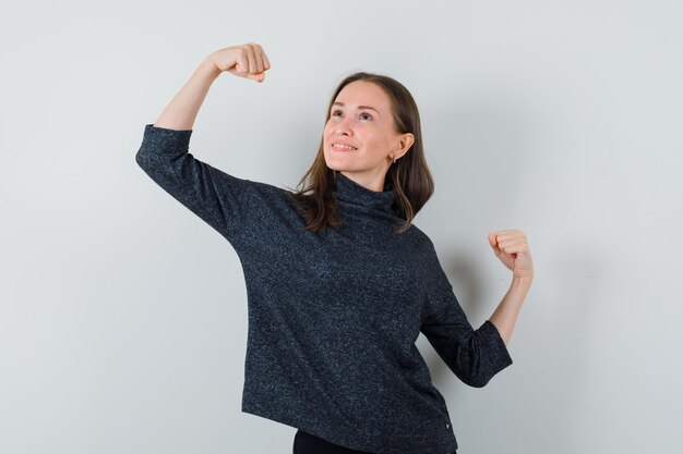 Young female in shirt showing winner gesture and looking dreamy 