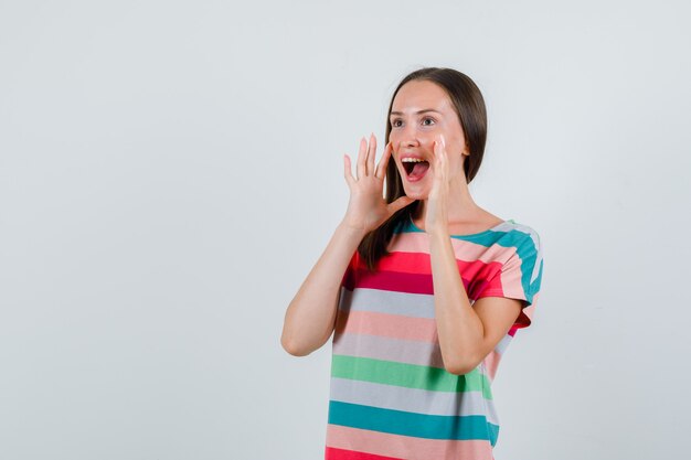 Young female shouting or announcing something in t-shirt , front view.