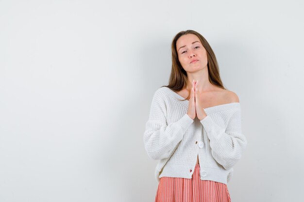 Young female showing namaste gesture in cardigan isolated