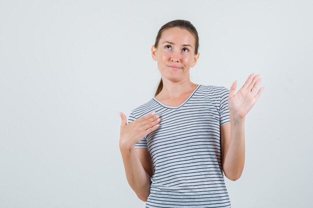縞模様のTシャツ、正面図で見上げながら手のひらを示す若い女性。