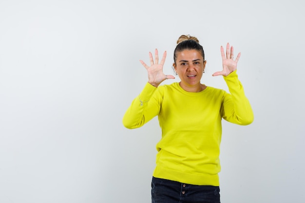 Young female showing palms in sweater, denim skirt and looking confident 