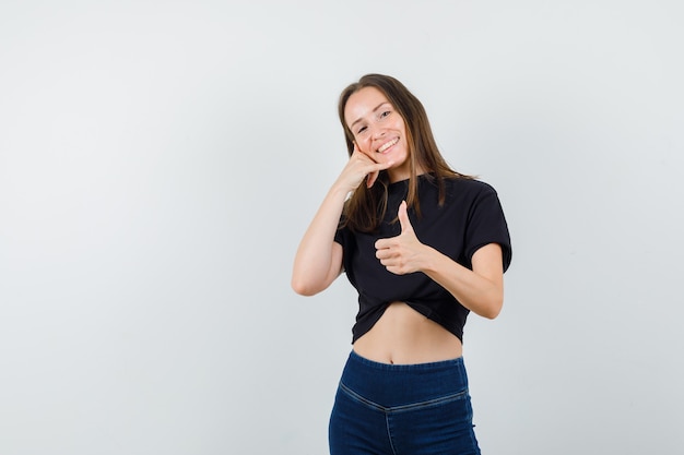 Free photo young female showing phone gesture and thumb up in black blouse