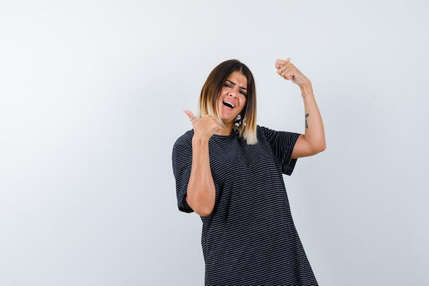 Young female showing thumbs up in polo dress and looking energetic. front view.