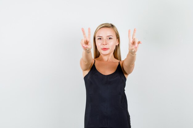 Free photo young female showing victory sign in black singlet and looking confident.