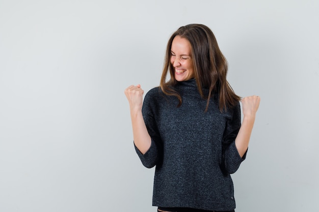 Free photo young female showing winner gesture in shirt and looking happy. front view.