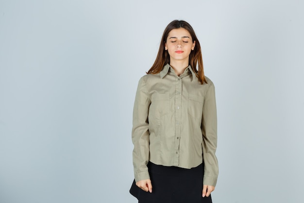 Free photo young female shutting eyes in shirt, skirt and looking dreamy