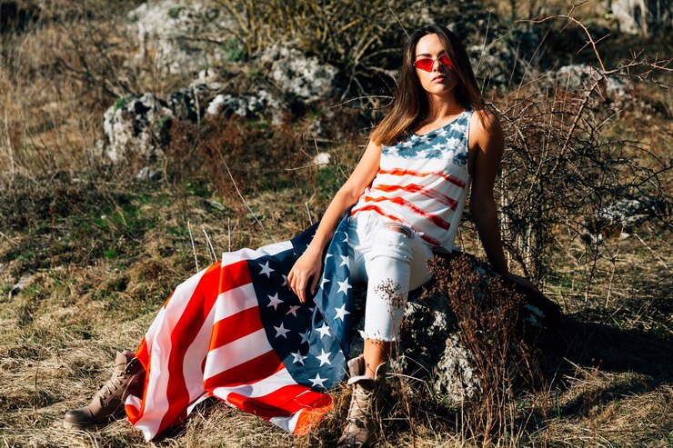 Free Photo young female sitting on stone with flag
