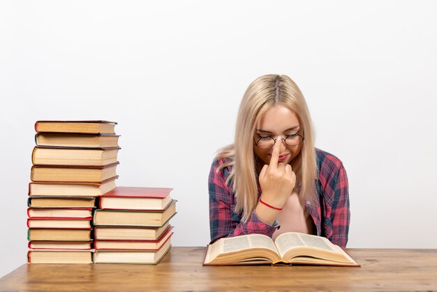 young female sitting with books and reading on white