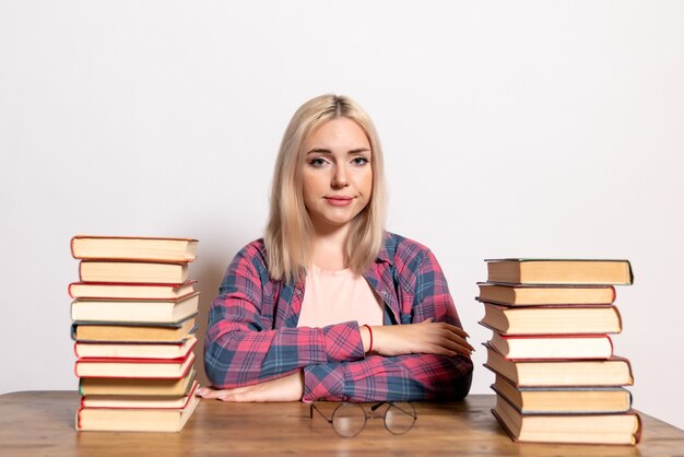 young female sitting with books on white