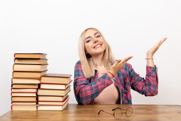 young female sitting with books on white