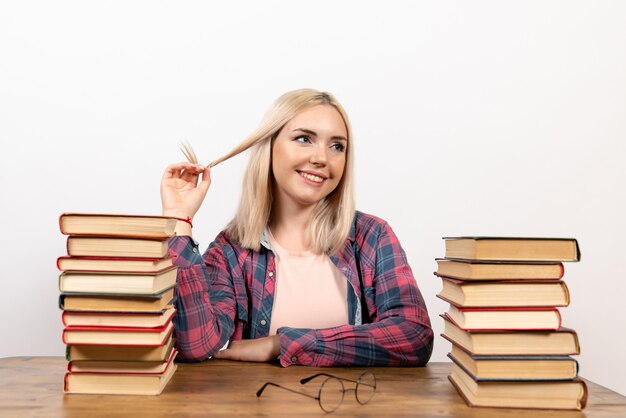 young female sitting with books on white