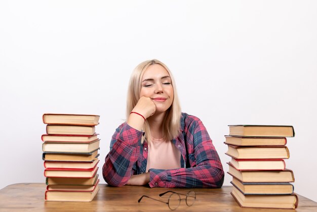 young female sitting with books on white