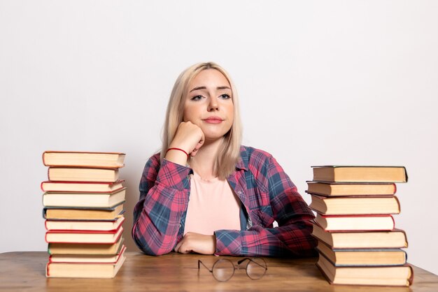 young female sitting with books on white