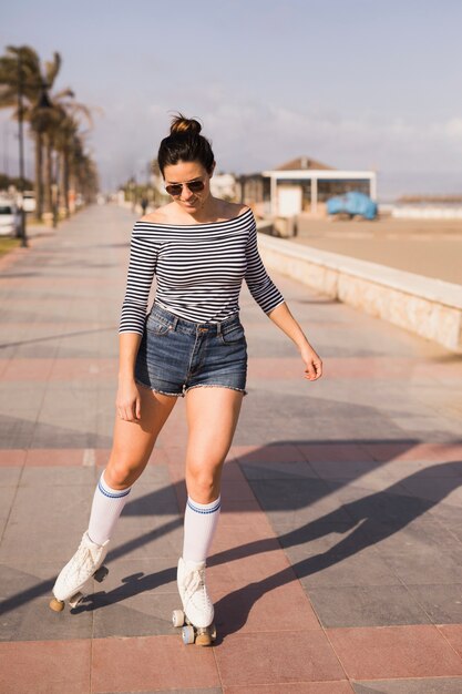 Young female skater skating on the sidewalk near the beach