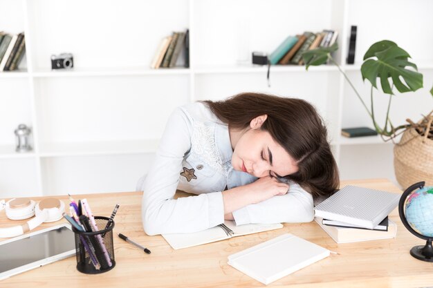 Young female sleeping on table in classroom 