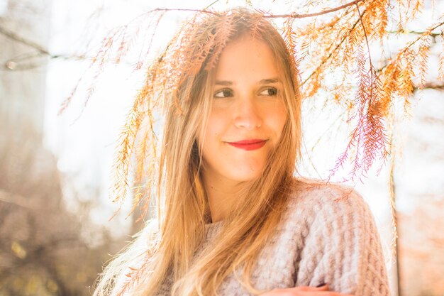 Young female smiles aside on autumn surface