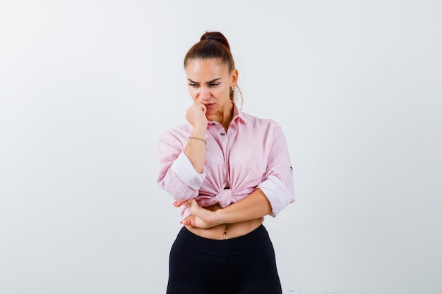 Free photo young female standing in thinking pose in casual shirt and looking pensive , front view.