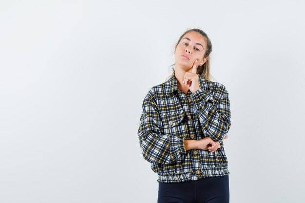 Young female standing in thinking pose in shirt, shorts and looking cute. front view.