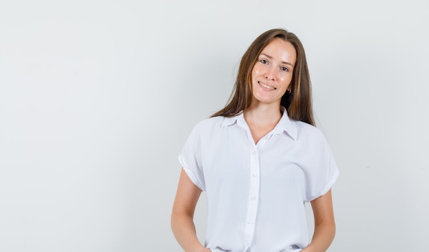 Young female standing in white blouse and looking confident.