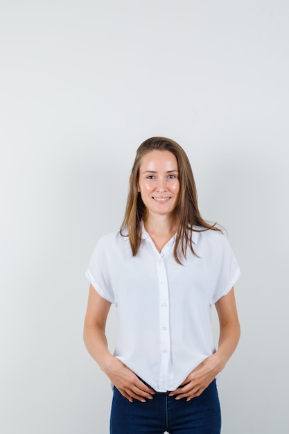 Молодая женщина стоит в белой блузке и смотрит оптимистично.