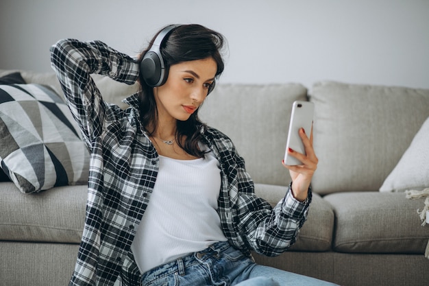 Молодая студентка прослушивания музыки через телефон на наушники