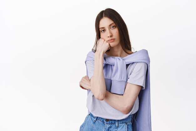 Young female student look bored and indifferent, resting head on palm and staring annoyed or tired of conversation, having boring meeting, standing over white background