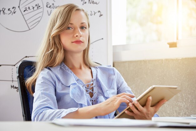 Young female student looking at camera holding the tablet PC