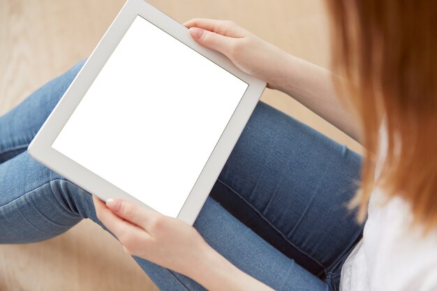 Young female student sitting in a university recreation hall using touch pad