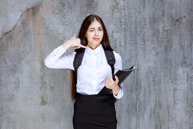 バックパックと本が立っている若い女子学生。高品質の写真