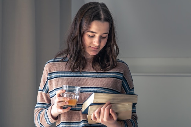 A young female student with books in her hands in the room