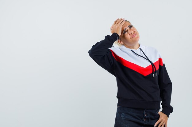 Young female suffering from headache in colorful sweatshirt and looking troubled. front view.